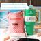 An orange bag with a circle print, is pictured beside a Stanley 40 ounce Quencher, chap stick, money and a cell phone.
